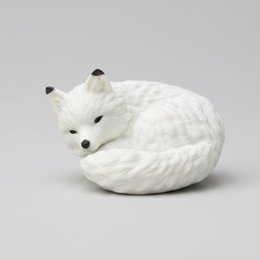 A white curled-up fox figurine with black eyes and nose,