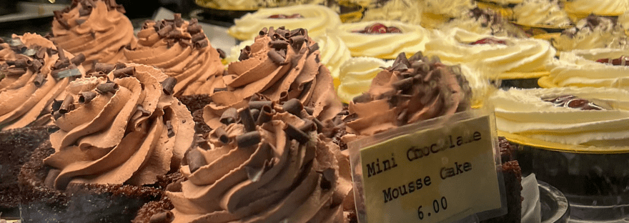 Dessert display case at Milwaukee Public Market with chocolate mousse cakes and pastries.