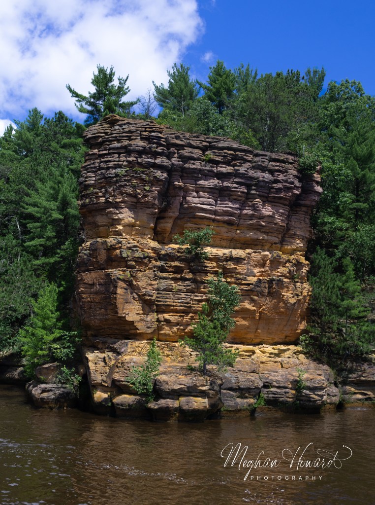 Massive sandstone pillar rising above the Wisconsin River with pine trees growing along the top in the Upper Dells